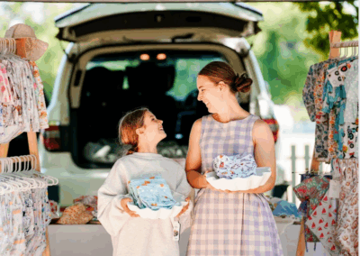 Mother and daughter holding baby clothes at market stall