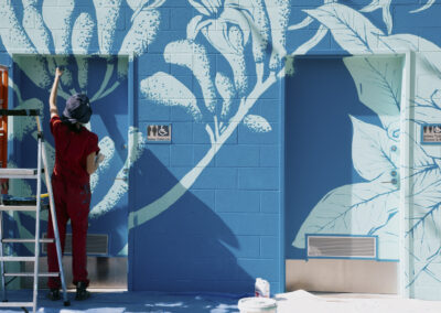 Aurora painting botanicals on the Visitor Centre wall.